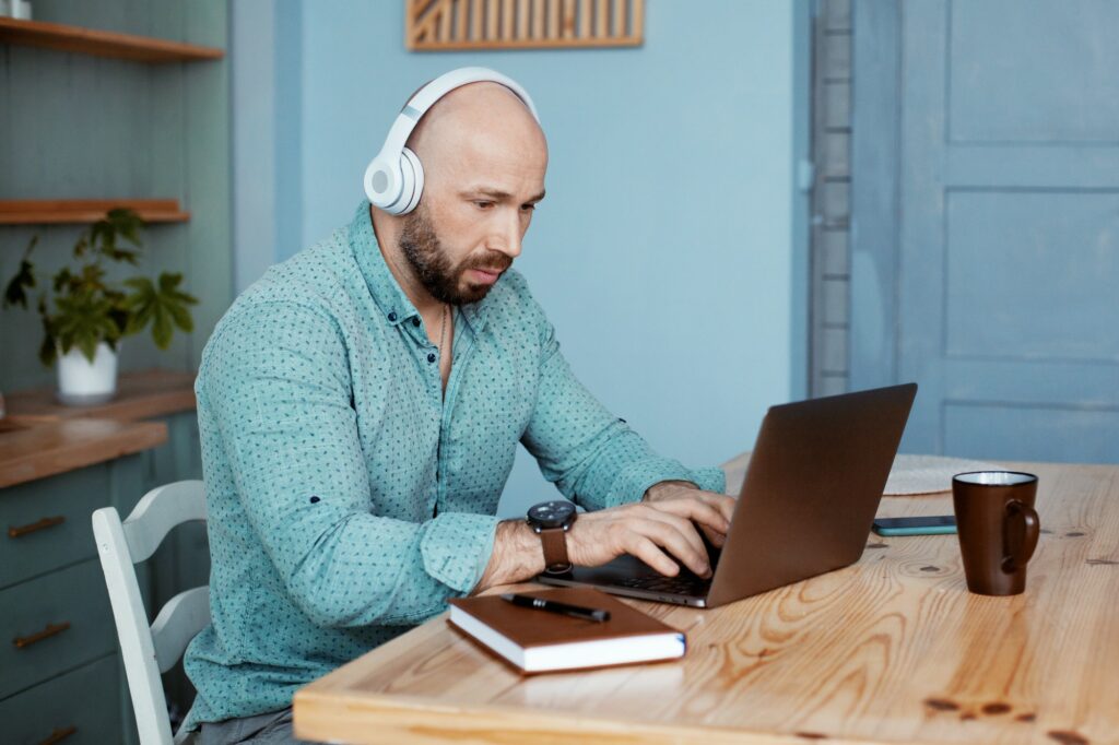 A businessman types text on a laptop and listens to music. Business without leaving home